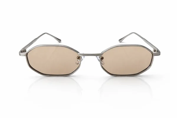 Lunettes de soleil de forme géométrique avec une monture argentée et des verres légèrement teintés, sur fond blanc.