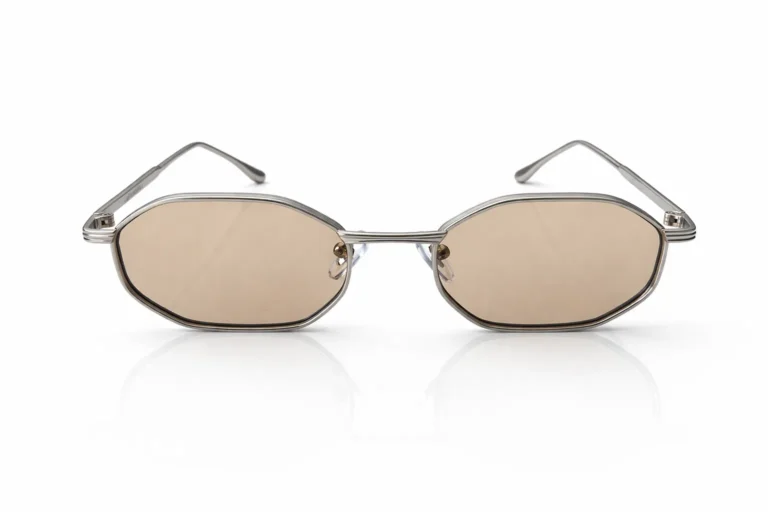 Lunettes de soleil de forme géométrique avec une monture argentée et des verres légèrement teintés, sur fond blanc.