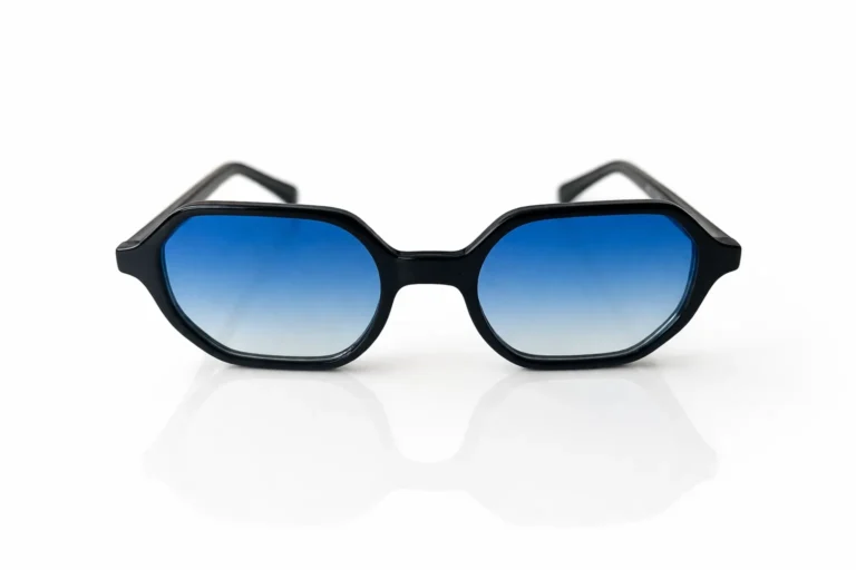 Lunettes de soleil noires à monture géométrique et verres bleus dégradés, présentées sur fond blanc.