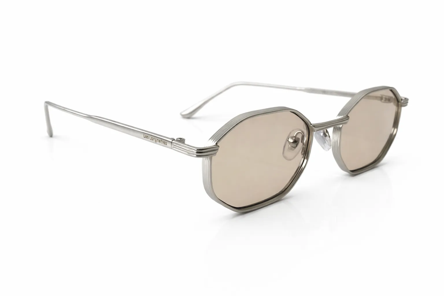 lunettes-de-soleil-octogonales-monture-argentee (1) Lunettes de soleil argentées à monture octogonale et verres teintés beige, vues de côté sur fond blanc.