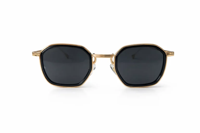 Lunettes de soleil octogonales avec monture dorée et verres noirs, vues de face sur fond blanc.