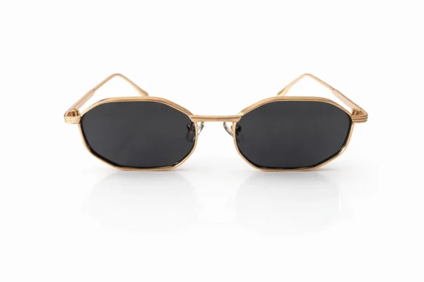 Paire de lunettes de soleil à monture dorée et verres noirs de forme octogonale, sur fond blanc.