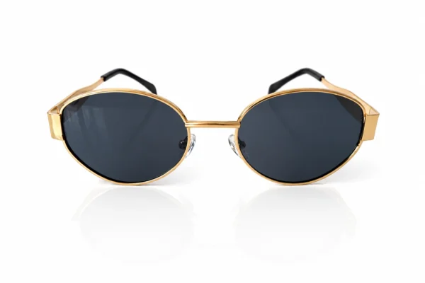 Gros plan sur des lunettes de soleil stylées à monture dorée et verres teintés foncés, posées sur fond blanc.