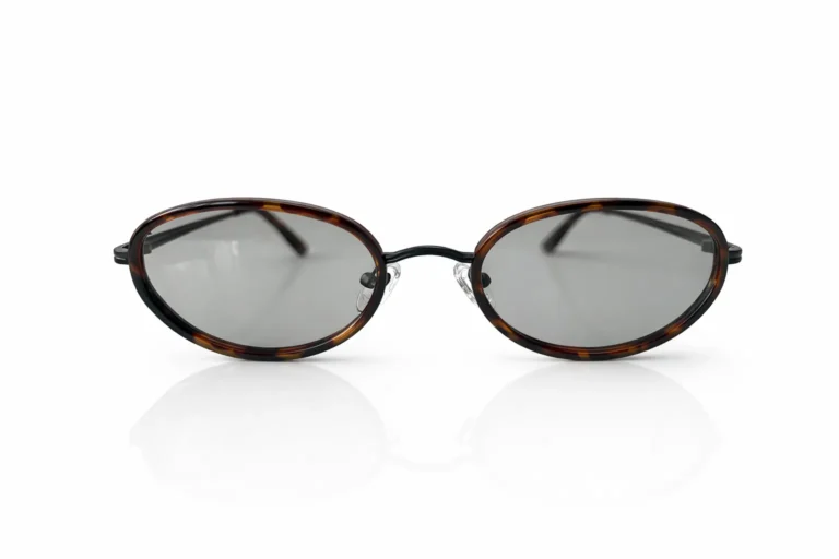 Lunettes de soleil ovales à monture écaille de tortue et verres gris clair, sur fond blanc.