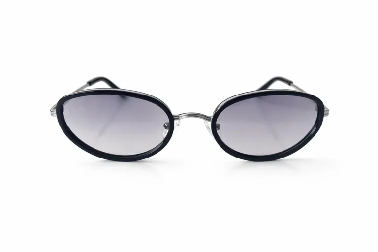 Lunettes de soleil noires avec une forme ovale tendance et des verres légèrement dégradés, présentées sur un fond blanc.