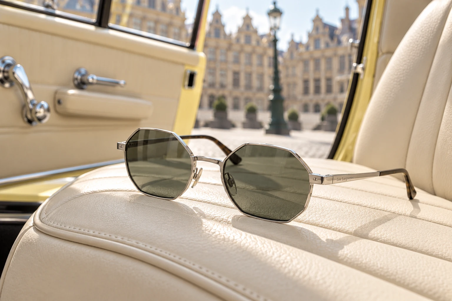 Lunettes de soleil octogonales Les Lorgnettes, monture argentée et verres verts, posées sur la banquette en cuir crème d’une voiture vintage